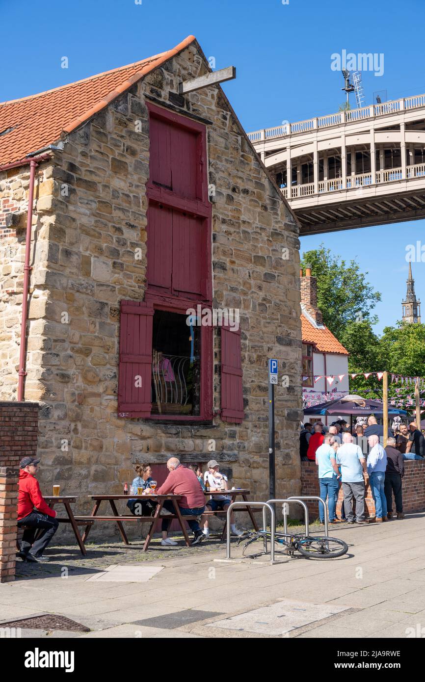 Das traditionelle Pub-Äußere und Leute, die außerhalb der Wetherspoons Quayside Bar an einem sonnigen Tag in Newcastle upon Tyne, Großbritannien, trinken. Stockfoto