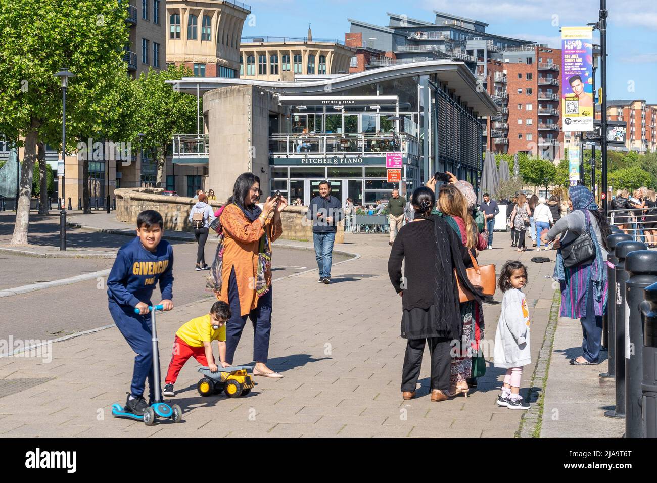 Eine Familie mit Frauen in traditioneller indischer Kleidung macht ein Selfie am Newcastle Quayside, Großbritannien, einem beliebten Touristenziel. Stockfoto