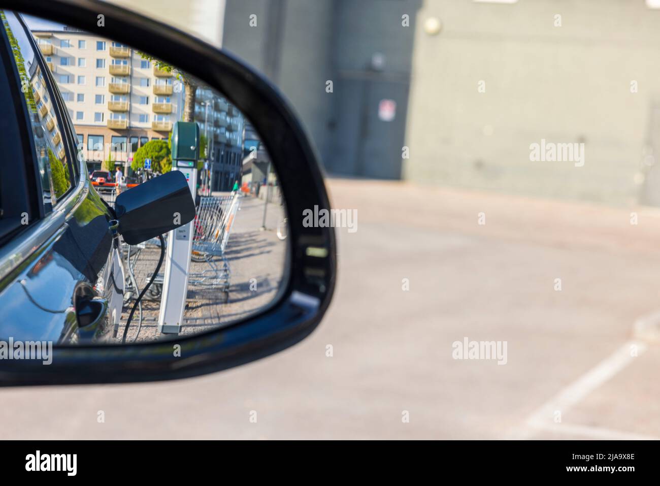 Blick in den Seitenspiegel des Elektroautos auf das Ladekabel von Connect. Schweden. Stockfoto