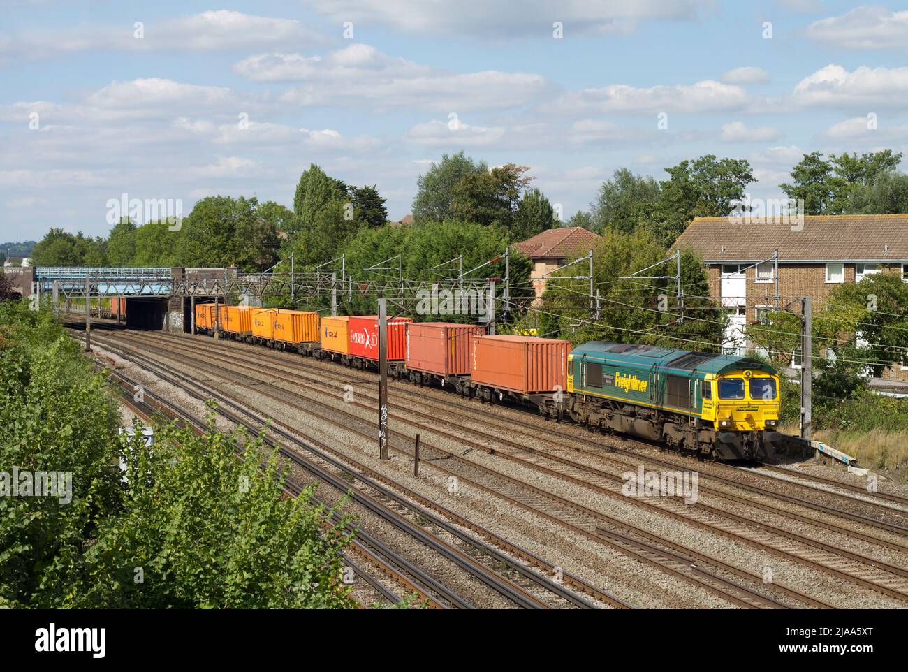 Eine Freightliner-Diesellokomotive der Baureihe 66 der Baureihe 66592 fährt mit einem Containerzug in Südkenton entlang der West Coast Mainline nach Süden. Stockfoto