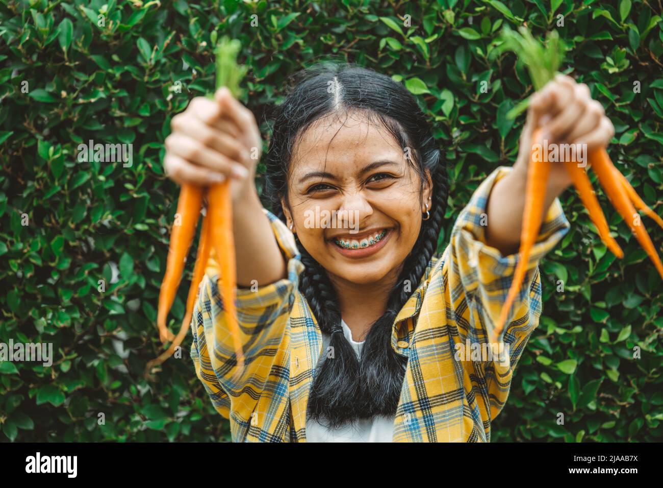 Essen vegan Gemüse für gesunde gut für das Leben Konzept. Junge Teenager Hand hält Baby Karotte glückliches Lächeln. Stockfoto