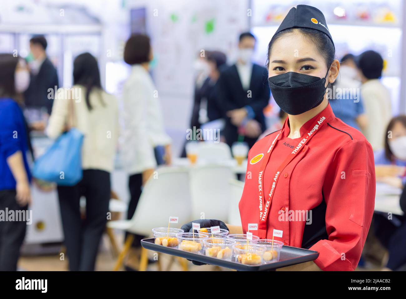 Lebensmittel-Produkte kostenlose Probe fördern Mädchen pritty Frau Modell zum Kunden zu Fuß in Food expo Festival Event Hall.25 Mai 2022.Bangkok, THAILAND. Stockfoto