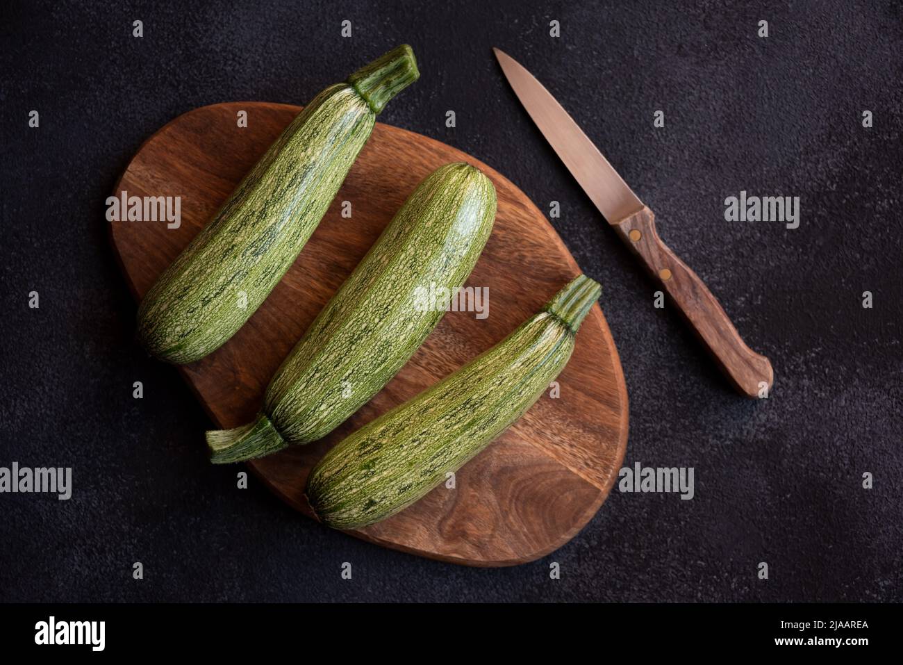 Frische Zucchini auf Holzschneidebrett mit Messer Stockfoto