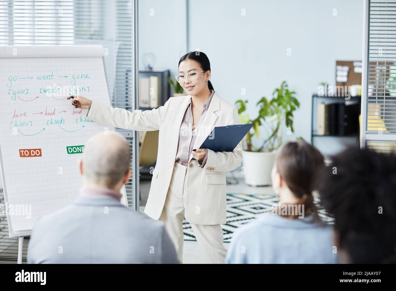 Porträt einer jungen asiatischen Frau, die im Büro Englischunterricht für eine Gruppe von Menschen gibt, Raum kopieren Stockfoto