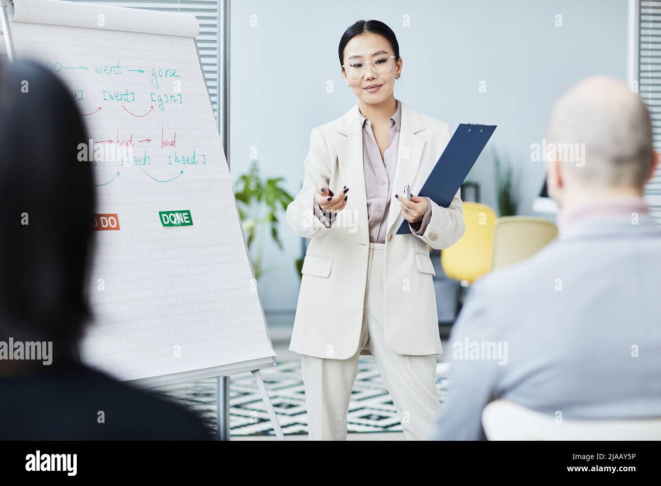 Porträt einer jungen asiatischen Frau, die im Büro Englischunterricht erteilt und am Whiteboard mit dem Publikum spricht Stockfoto