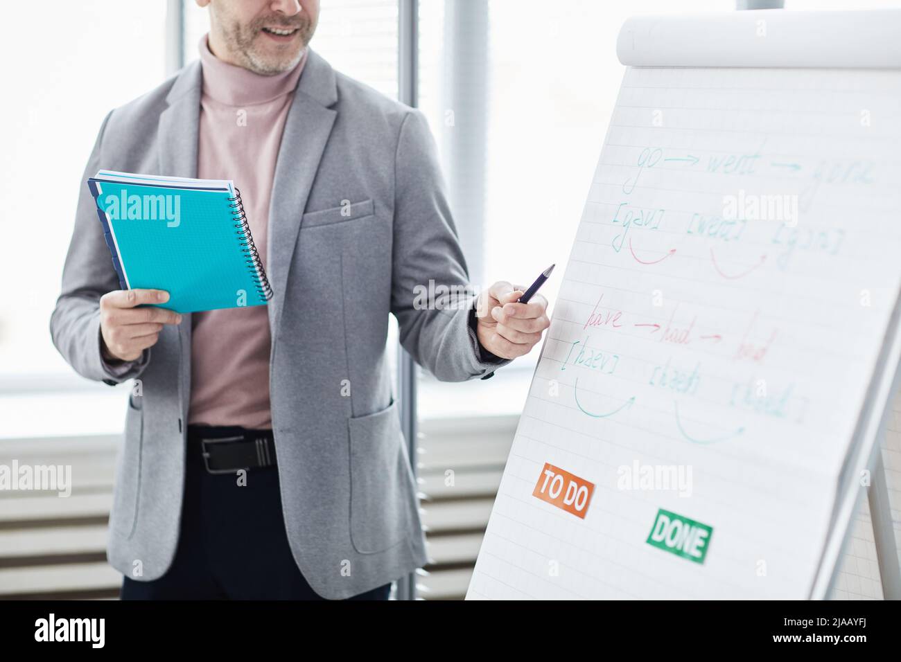 Ausgeschnittene Aufnahme eines reifen männlichen Lehrers, der im Büro Englischunterricht erteilt und auf das Whiteboard zeigt und Platz zum Kopieren bietet Stockfoto