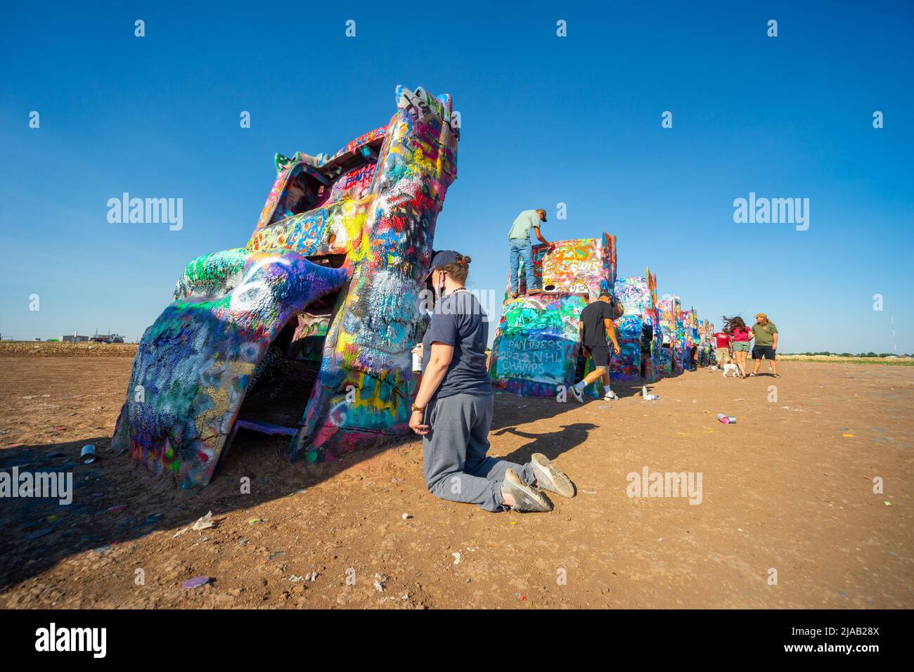 Cadillac Ranch, eine Kunstinstallation in der Nähe von Amarillo, TX, USA. Ein Künstler sprüht Farbe auf eines der Autos. Route 66 Stockfoto