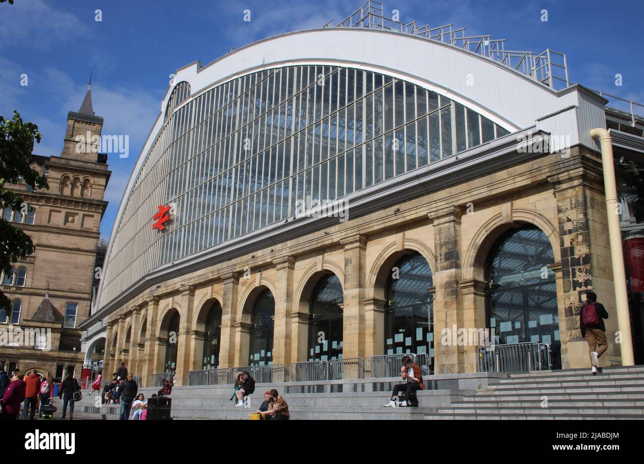 Blick auf den Außen- und Haupteingang des Bahnhofs Liverpool Lime Street in Liverpool, England, mit Leuten, die am 27.. Mai 2022 draußen auf Treppen saßen. Stockfoto