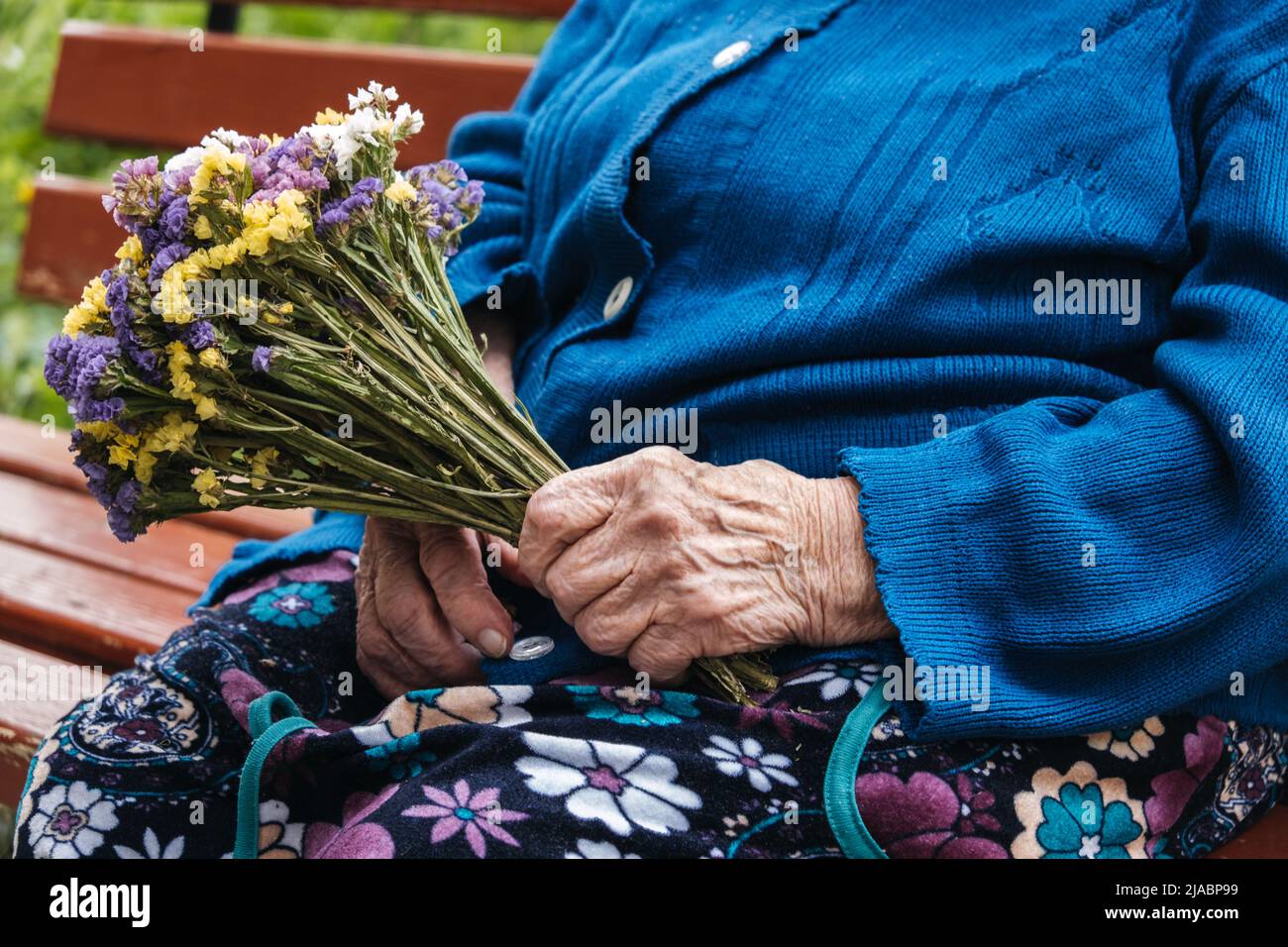 Unterstützung durch leitende Mitarbeiter. Wohltätigkeitsorganisationen für ältere Menschen. Nahaufnahme von Händen älterer Frauen mit Blumenstrauß. Stockfoto