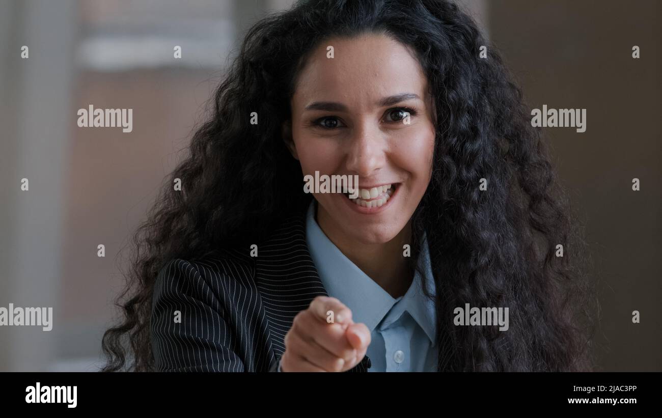 Arabisch lächelnde lockige Frau Angestellte Geschäftsfrau zeigt Zeigefinger auf Kamera emotional sprechend erklärt Corporate Items hey Sie Geste Stockfoto