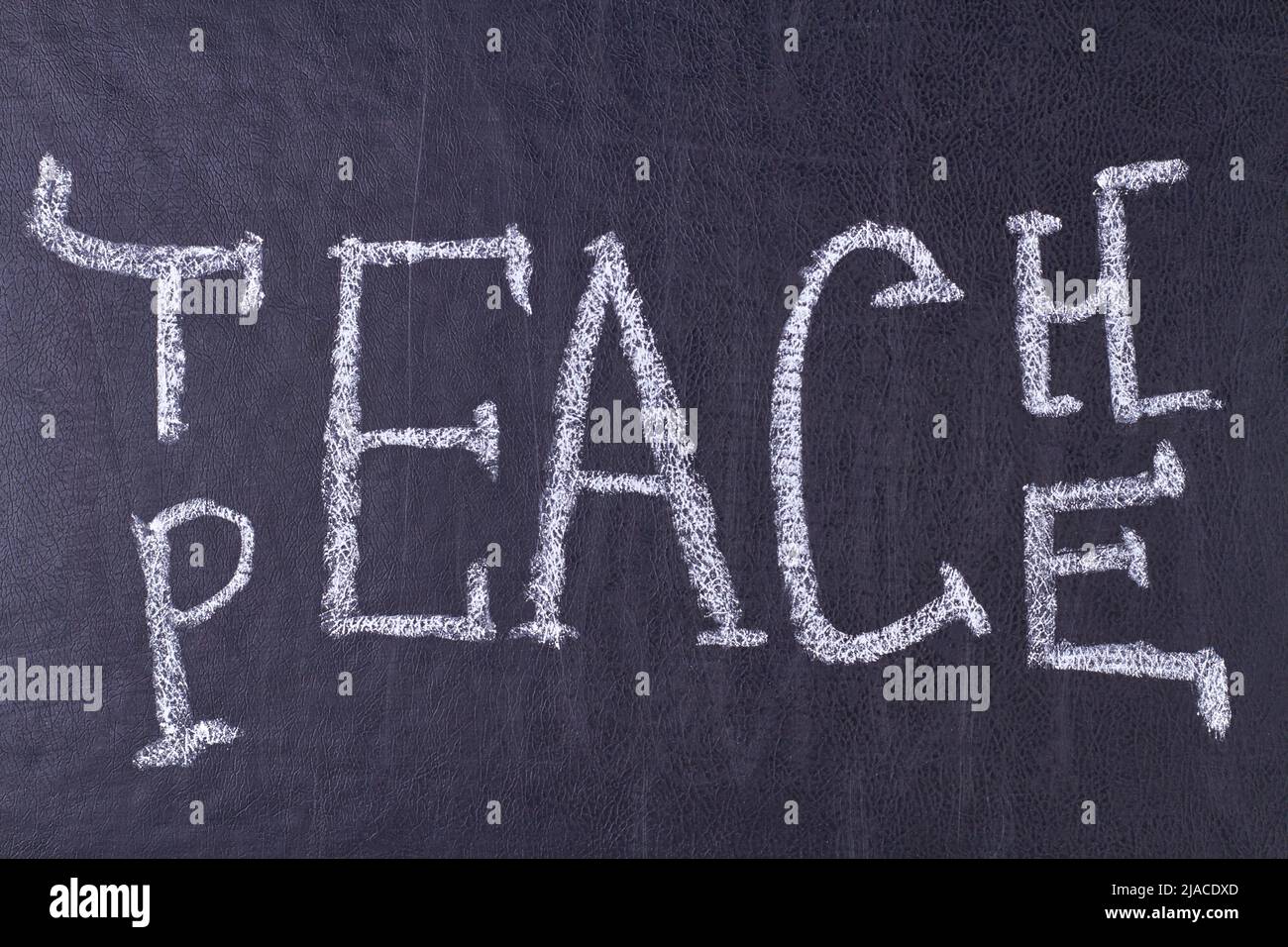 Wort lehren Frieden geschrieben auf schwarzer Tafel Nahaufnahme. Bildung und Menschlichkeit Konzept. Stockfoto