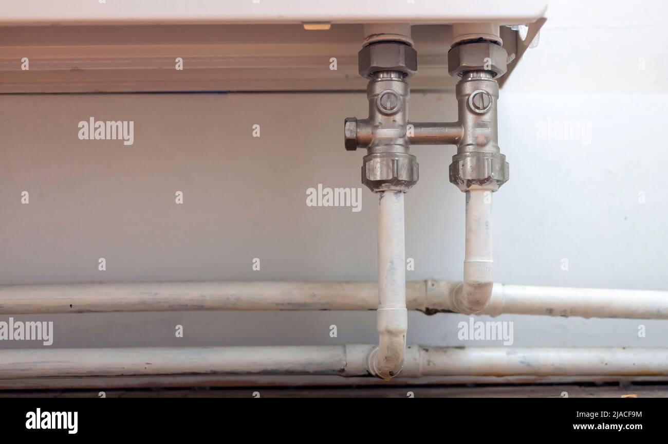 Konzept der Zentralheizung. Altmodischer stationärer gusseiserner Heizkörper mit Heizrohr, metallischer Anschluss für warme Winternächte. Stockfoto