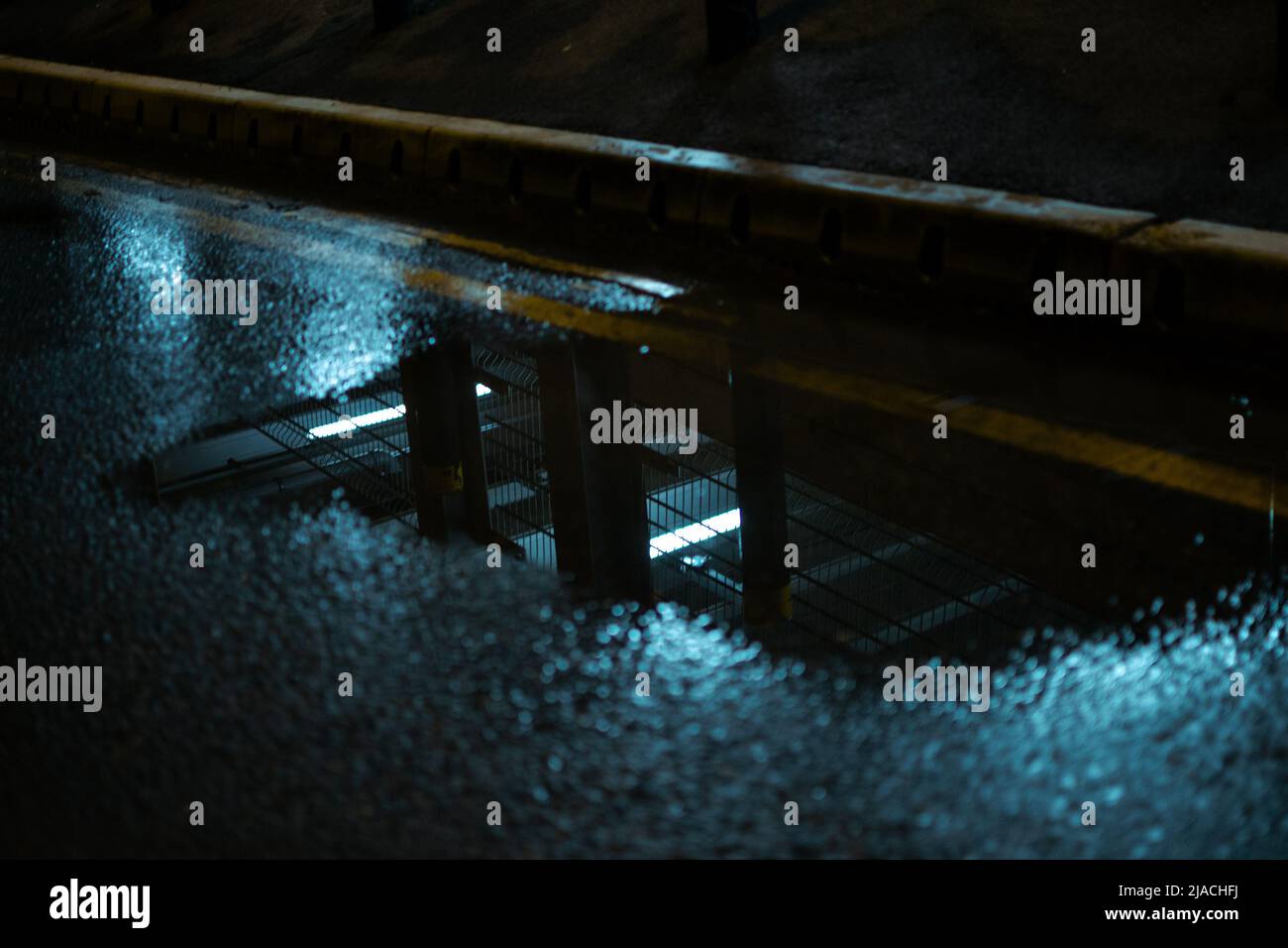 Spiegelbild eines mehrstöckigen Parkplatzes in einer Pfütze, gelegen am Manchester International Airport, Greater Manchester, Großbritannien. Stockfoto