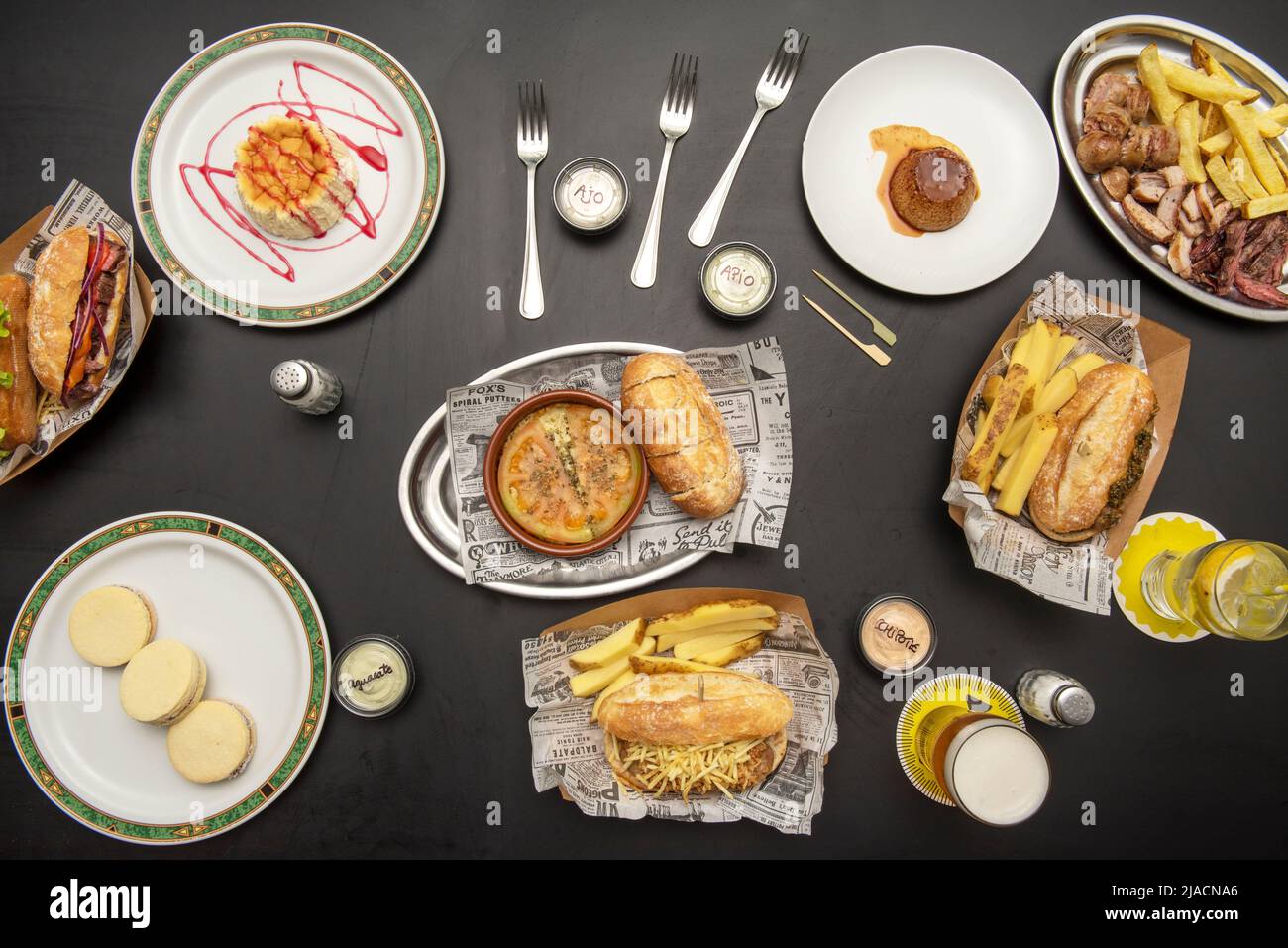 Verschiedene Teller mit Sandwiches, pommes frites, Roastbeef in Scheiben, Panna Cotta und Käsekuchen Stockfoto