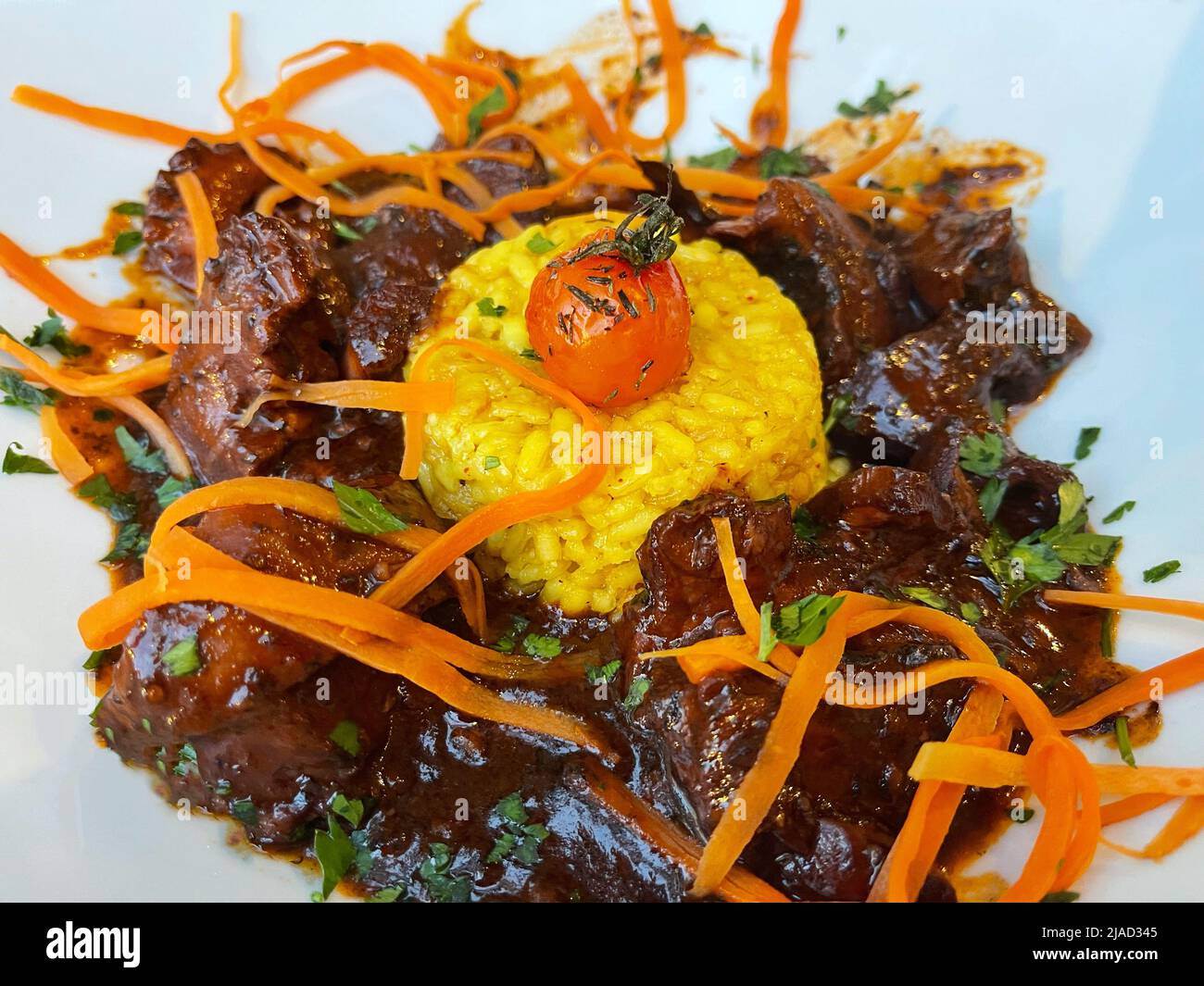 Nahaufnahme des Tintenfischeintopfs mit Safranrisotto und Karottengarnitur Stockfoto