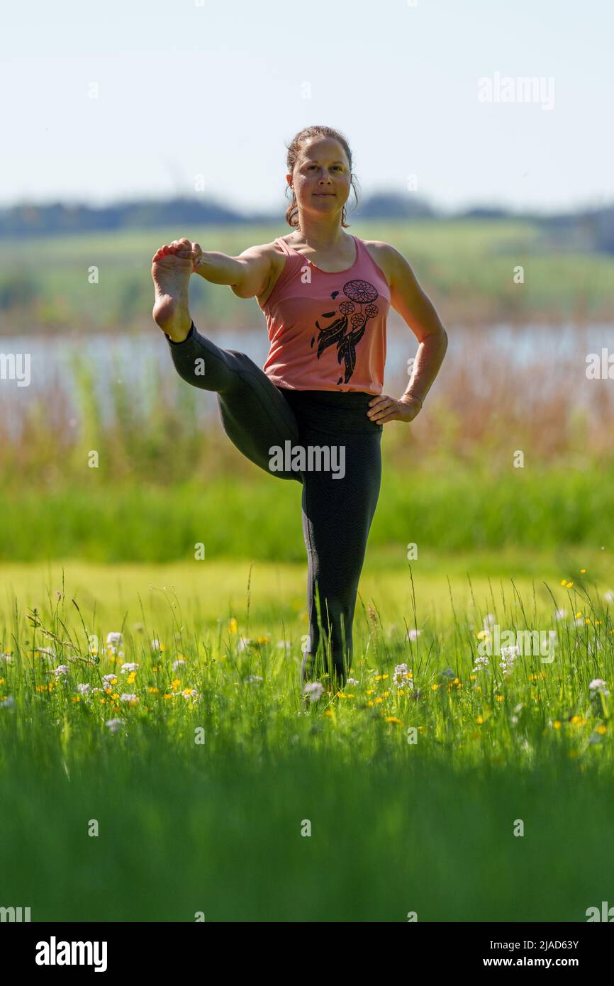 Woman doing standing Hand to Big Toe Pose von Wallersee, Salzburg, Österreich Stockfoto