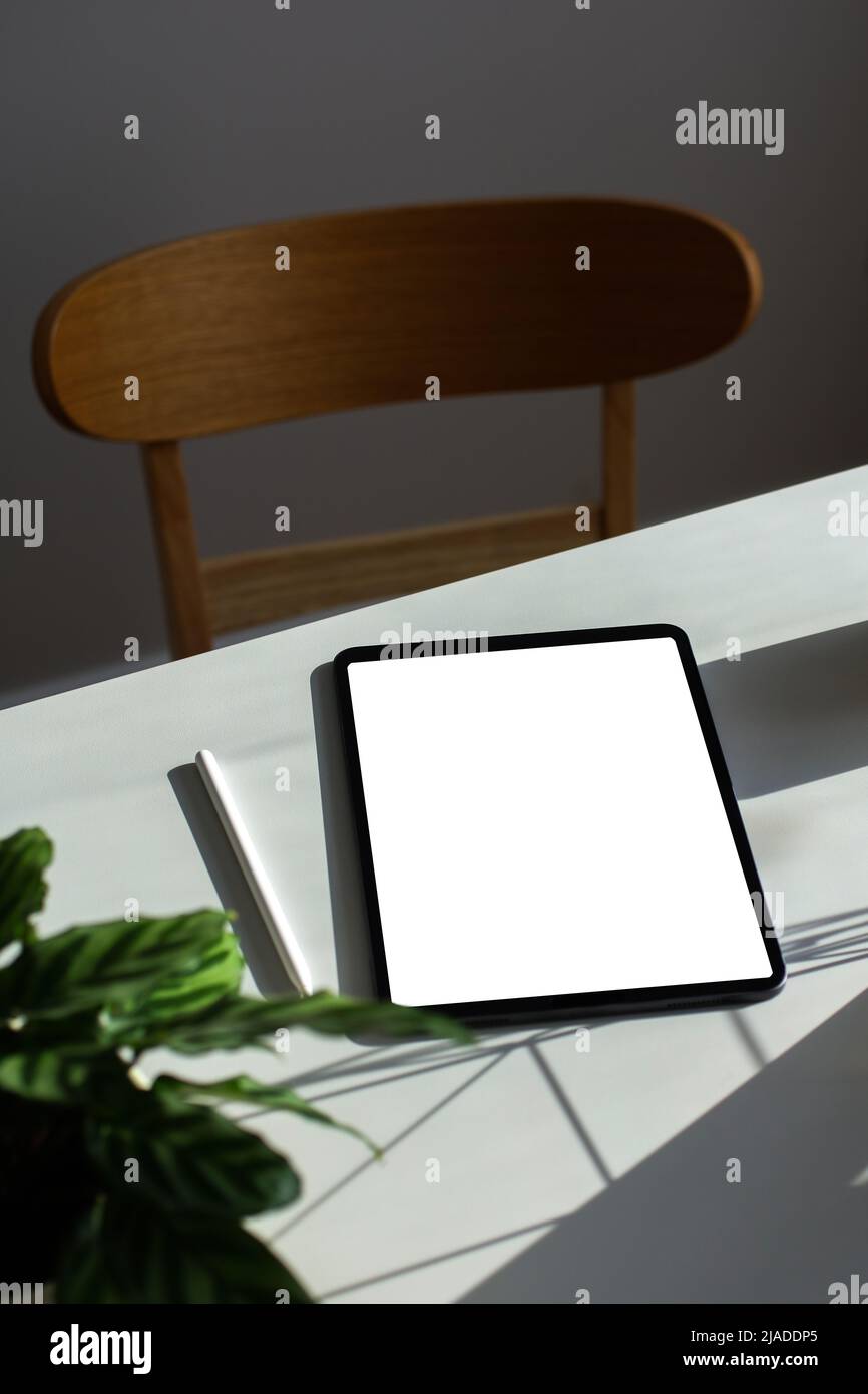 Digitales Tablet mit leerer Bildschirmvorlage auf dem Schreibtisch des Heimbüros. Ästhetischer femininer Arbeitsplatz in Sonnenlichtern Stockfoto