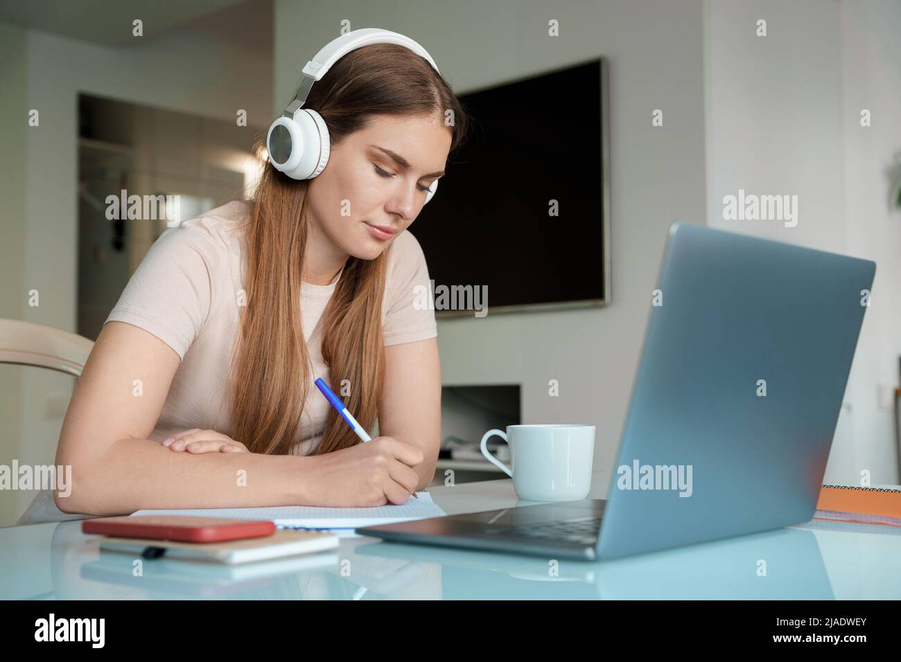 Teenager mit Kopfhörern, die im Heimbüro einen Laptop für Online-Studien verwenden Stockfoto