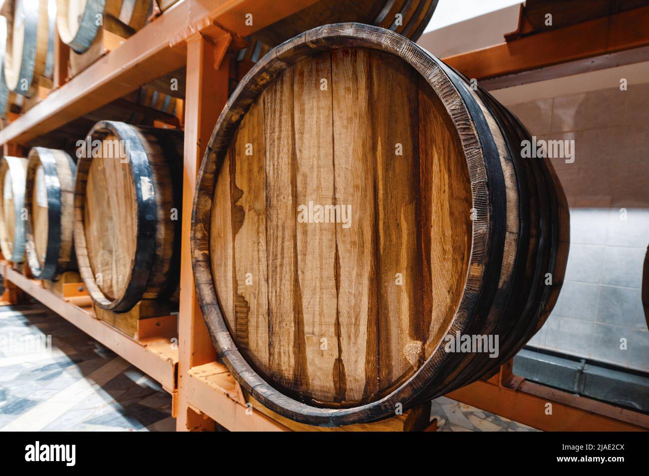 Riesige Holzfässer mit alkoholischen Getränken auf Regalen im Keller Stockfoto