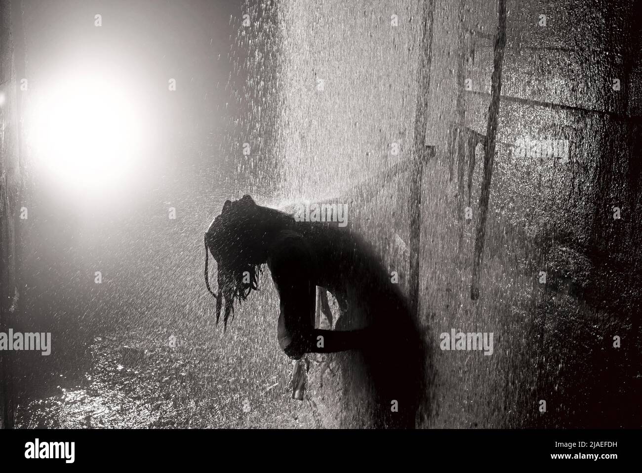 Junge Frau unter Wasserstrahlen in die Kanalisation. Stockfoto