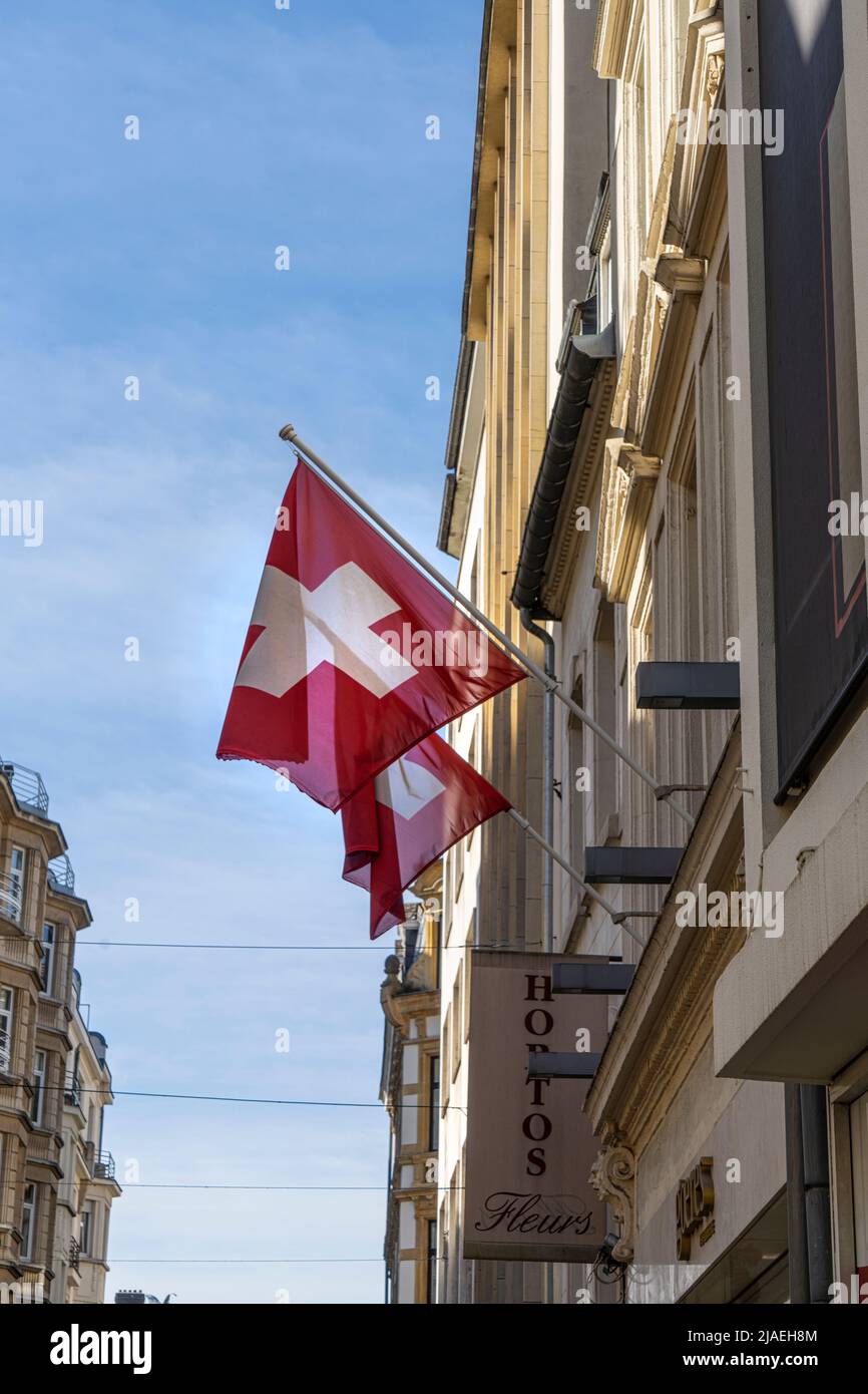 Luxemburg, 2022. Mai. Zwei Schweizer Flaggen winken auf einer Straße im Stadtzentrum Stockfoto