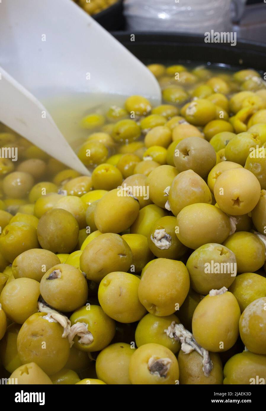 Eingelegte Oliven gefüllt mit Essig eingelegte Sardellen. Köstliche eingelegte Snack angezeigt Plastikkorb Stockfoto
