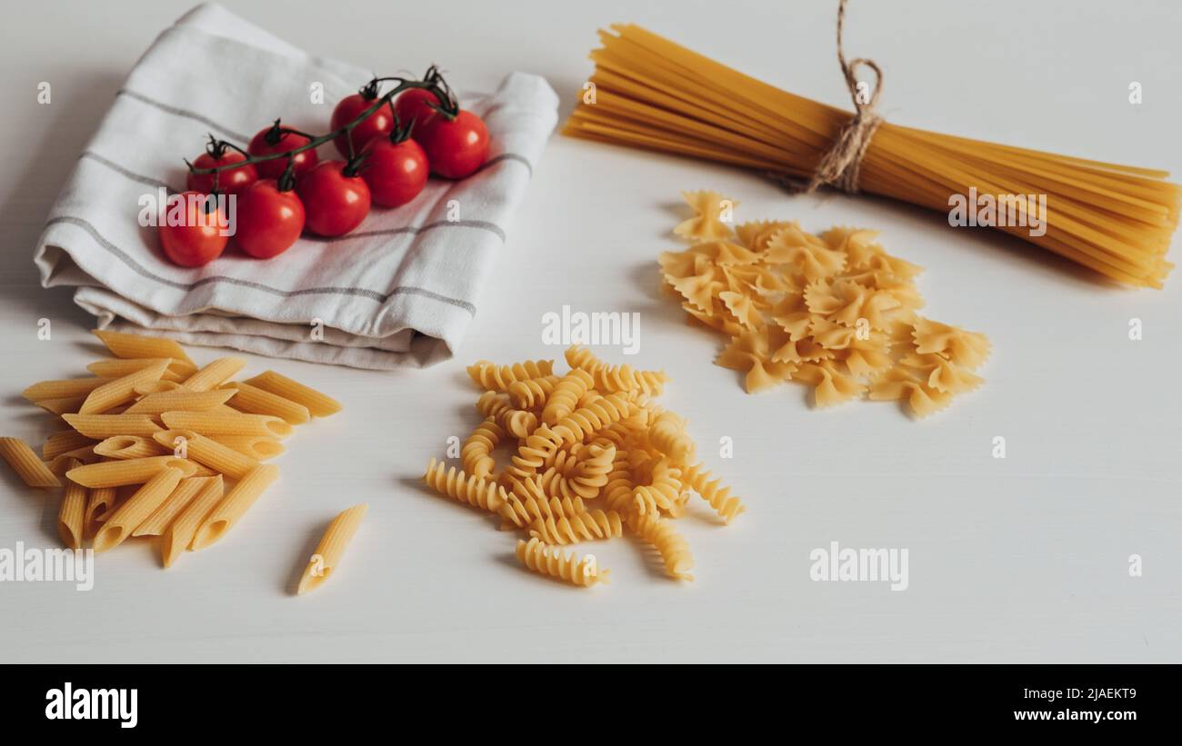 Verschiedene Arten von Pasta und Kirschtomaten auf dem Küchentisch Stockfoto