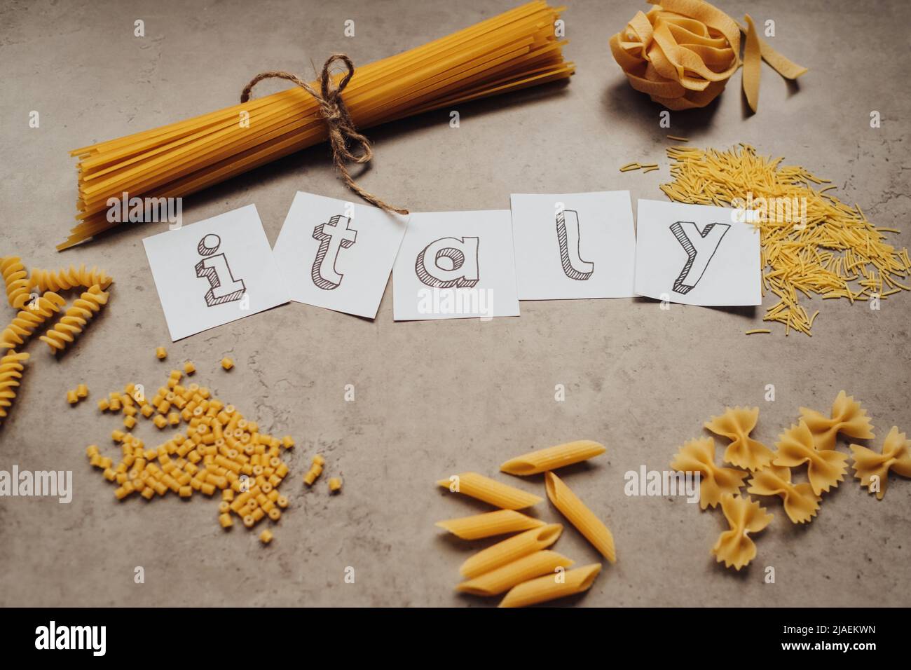 Schriftzug mit verschiedenen Nudelsorten und einer Handvoll Spaghetti auf dem Tisch Stockfoto