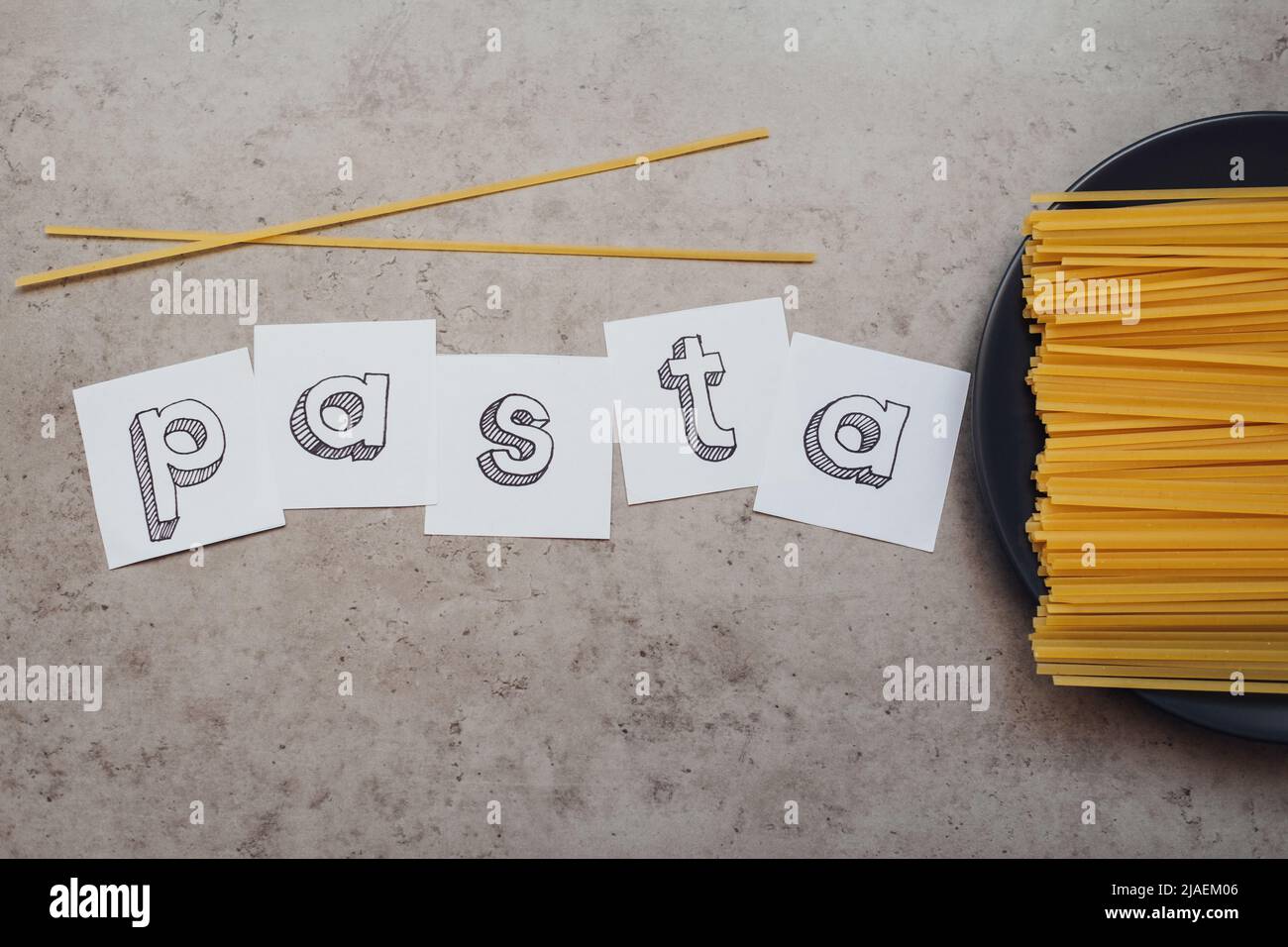Schriftzug mit einer Handvoll Spaghetti auf dem Tisch Stockfoto