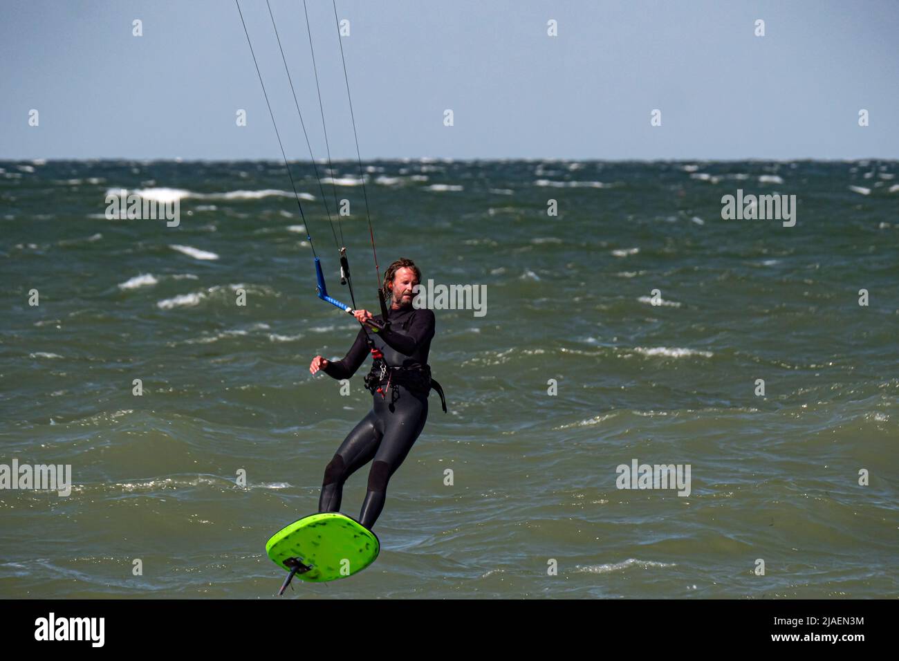 Kitesurfer mit Bart und langen Haaren auf dem Meer. Nahaufnahme Stockfoto
