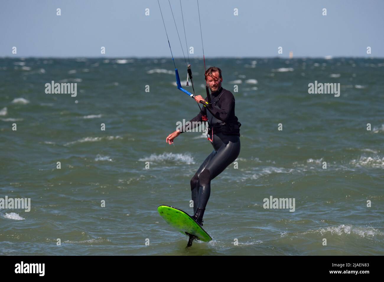 Kitesurfer mit Bart und langen Haaren auf dem Meer. Stockfoto