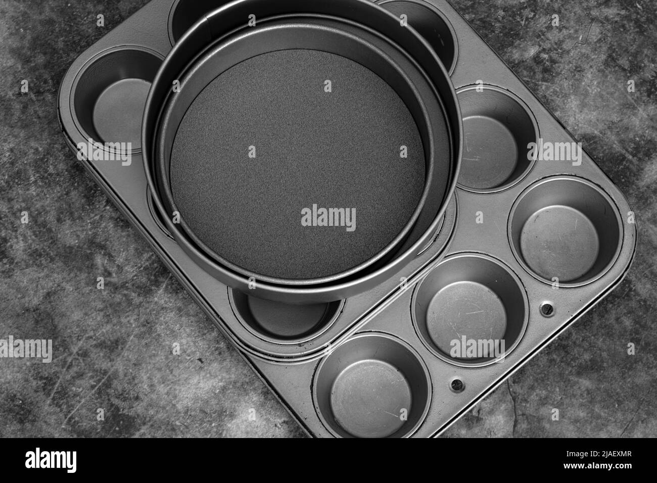 Backbleche und Kuchenformen auf schwarzem Steingrund. Kochgeschirr Konzept Stockfoto
