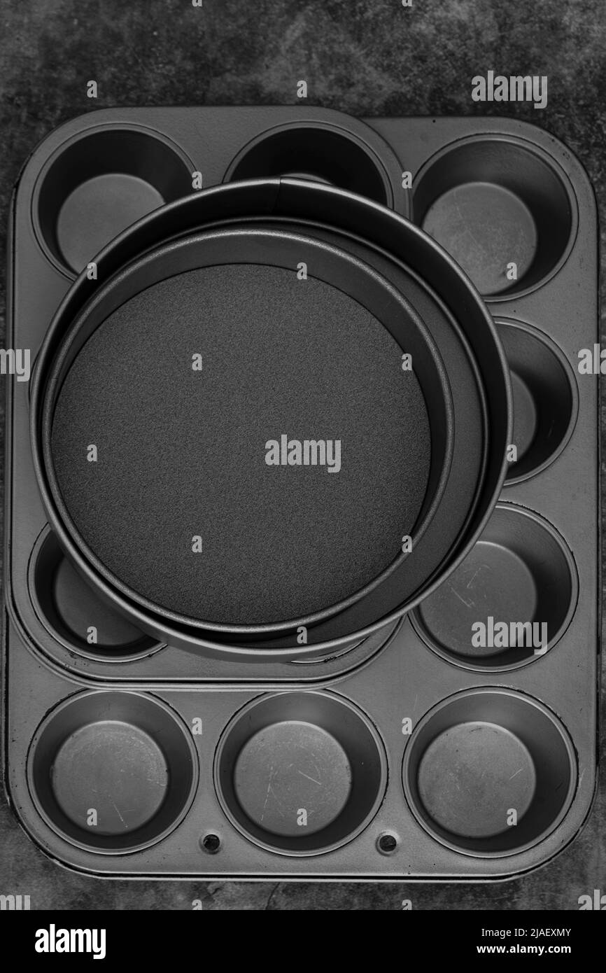 Backbleche und Kuchenformen auf schwarzem Steingrund. Kochgeschirr Konzept Stockfoto