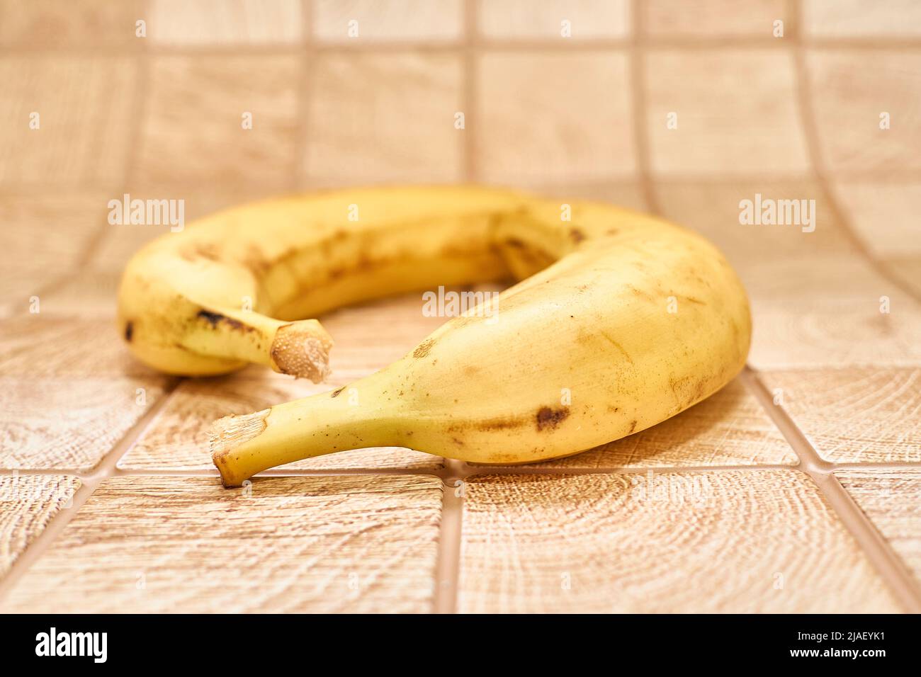 Zwei reife Bananen auf einer karierten Holzoberfläche Stockfoto