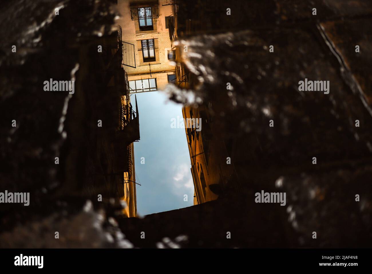 Pfütze Reflexion des Gebäudes mit blauem Himmel in Spanien. Wasserpuddle auf Stein mit Architektur. Stockfoto