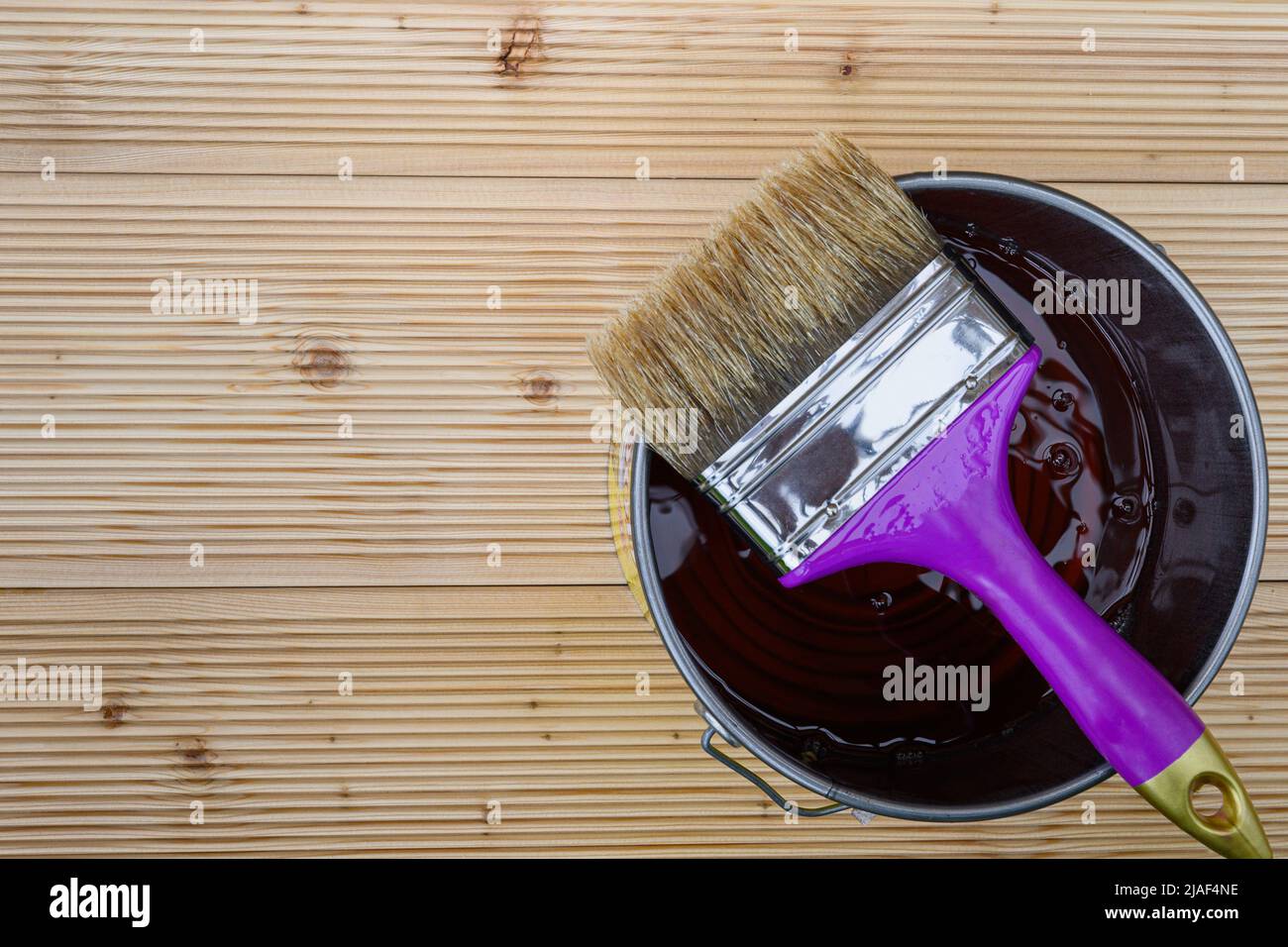 Neue Holzbretter für Terrasse mit speziellem Schutzöl lackieren. Ein Glas wasserdichtes Schutzöl mit Bürste zum Abdecken von Lärchenböden vor schlechtem Wetter Stockfoto