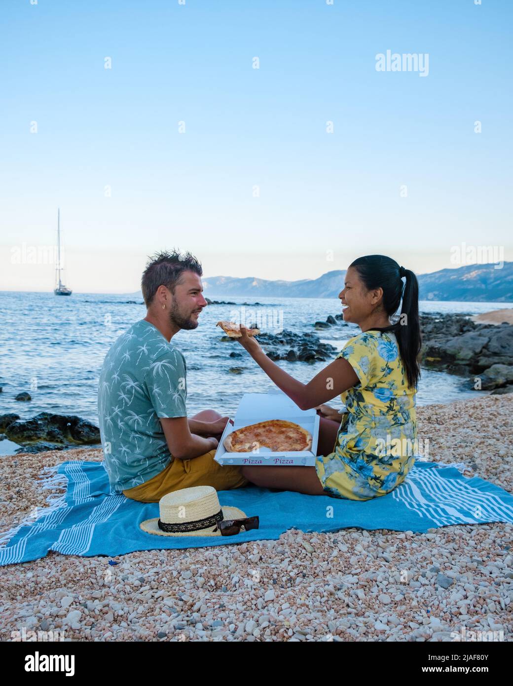 Golfo di Orosei Sardina, Männer und Frauen am Strand Pizza essen, glückliche Männer und Frauen am Strand mit Pizza in Italien. Stockfoto