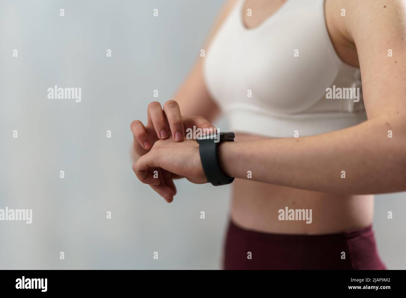 Nahaufnahme der Einstellung einer jungen Frau und des Anschauens einer Sport-Smartwatch. Fitness-Frau überprüft ihre Leistung. Stockfoto