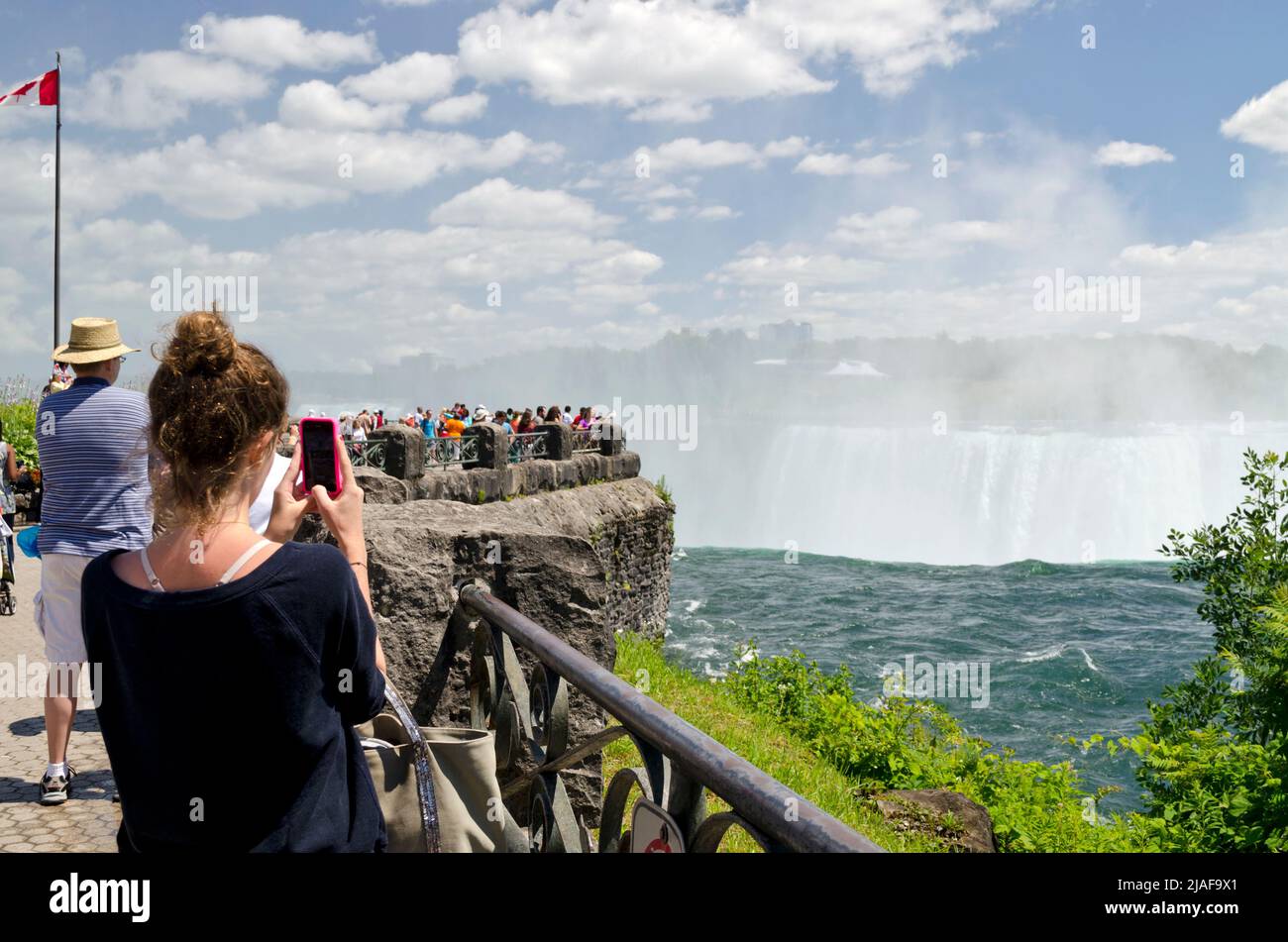 Frau, die ein Foto von den Niagarafällen mit ihrem Handy von der kanadischen Seite in Niagara Falls, Ontario, Kanada, macht Stockfoto