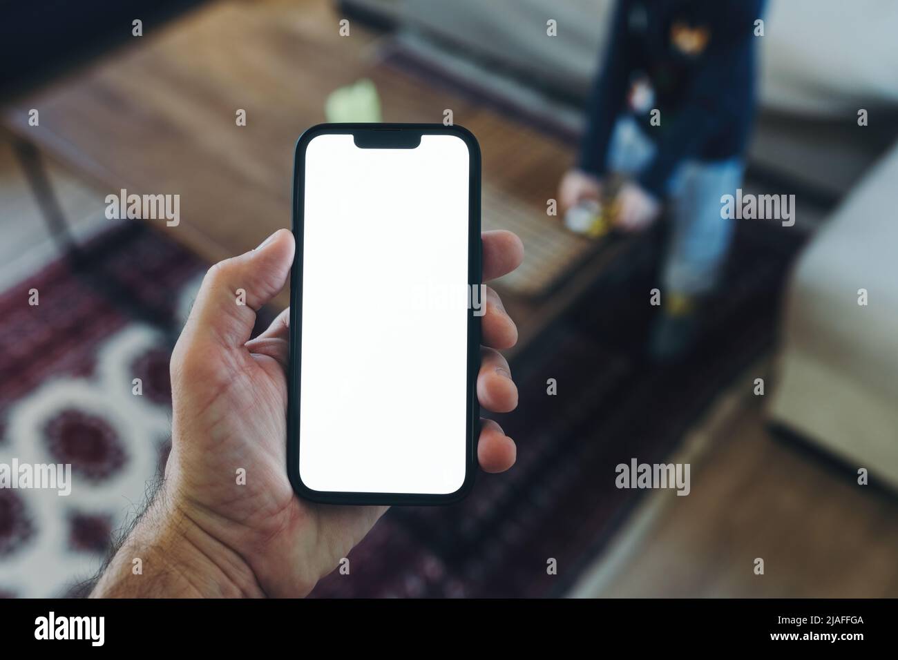 Smartphone-Mockup, Internet der Dinge und Smart-Home-Konzept, Mann mit Mobiltelefon. Nahaufnahme der Handhaltevorrichtung mit leerem Bildschirm im Home Interi Stockfoto