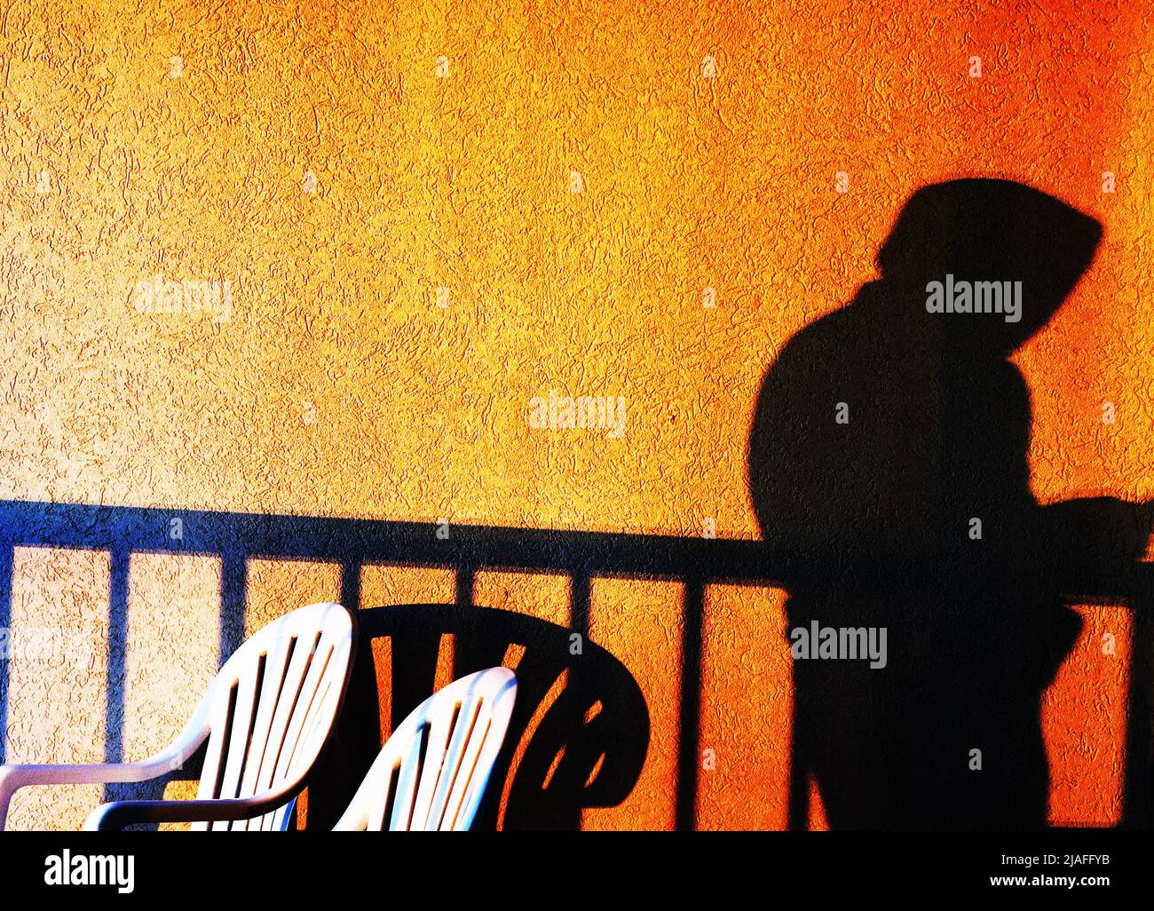 DOBBELGANGER:Der Schatten Eines Mannes trennt sich von einem selbst, das in Zeit und Bewusstsein invertiert ist, für ein Selfie eines Balkons bei Sonnenaufgang. Stockfoto