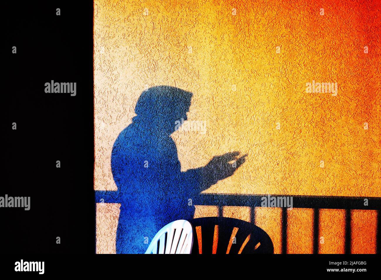 DOBBELGANGER:Der Schatten Eines Mannes trennt sich von einem selbst, das in Zeit und Bewusstsein invertiert ist, für ein Selfie eines Balkons bei Sonnenaufgang. Stockfoto