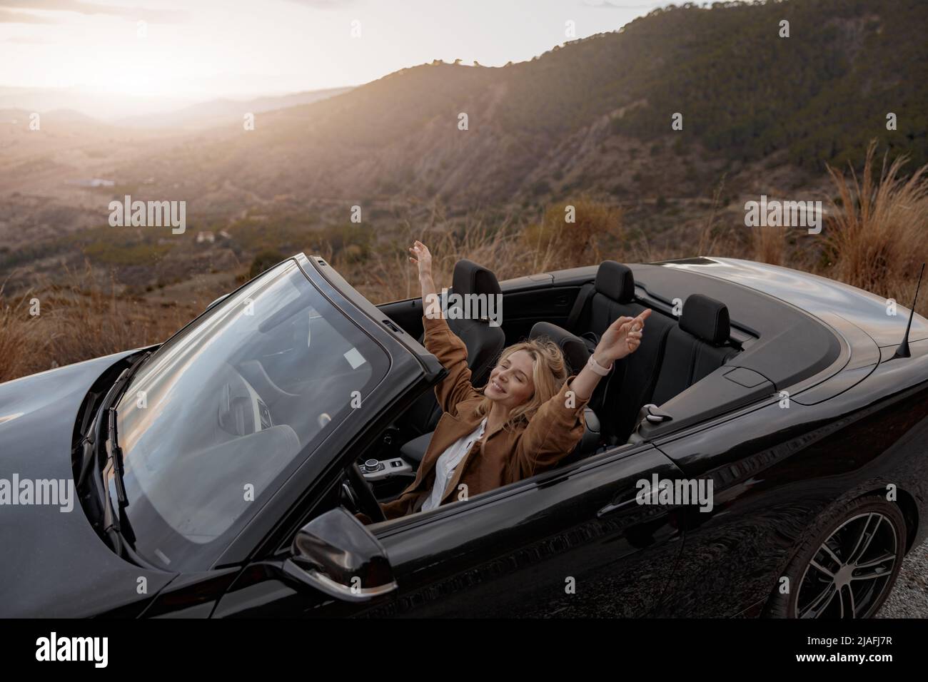 Kaukasische schöne glückliche Frau entspannt sitzen im Cabrio allein reisen Gefühl frei Stockfoto