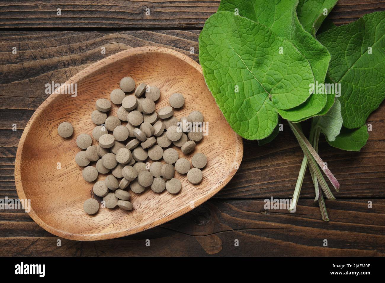 Klettenblätter und Pillen mit Extrakt aus arctium lappa - lateinischer Name für Klette. Draufsicht. Stockfoto
