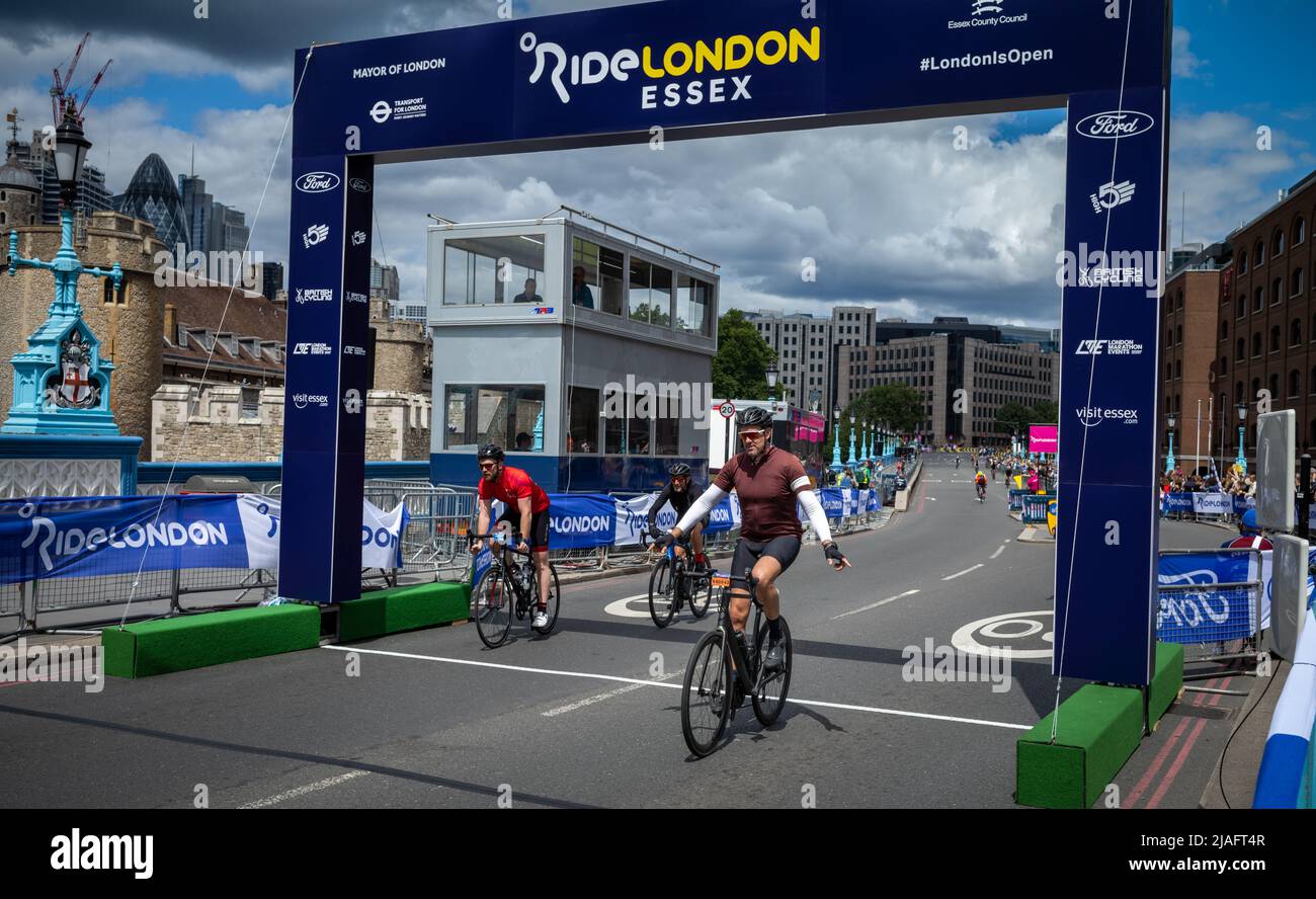 Ein Radsportler, der an der RideLondon 2022 teilnimmt, streckt seine Arme aus, als er die Ziellinie auf der Tower Bridge in London überquert. Die Veranstaltung fand für Th statt Stockfoto