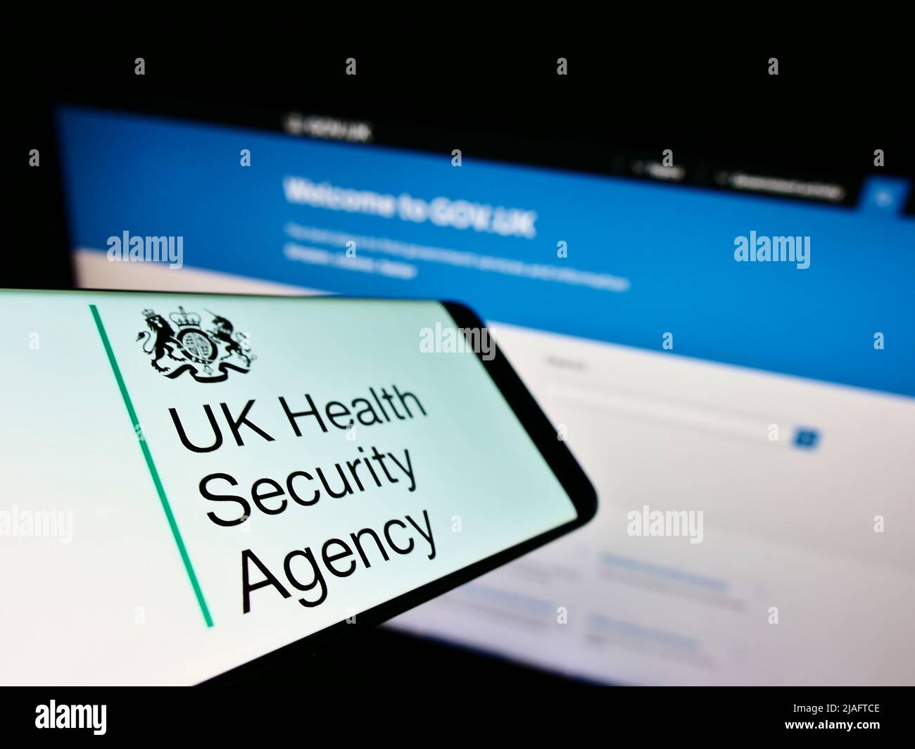 Handy mit Logo der britischen Gesundheitsbehörde (UKHSA) auf dem Bildschirm vor der Website. Konzentrieren Sie sich auf die Mitte links des Telefondisplays. Stockfoto