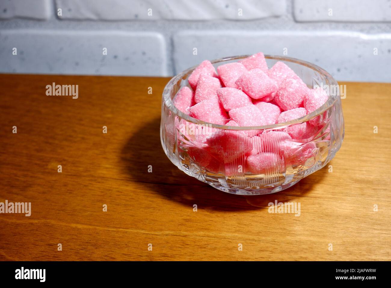 Kristallschale mit rosa Süßigkeiten auf dem Tisch Stockfoto