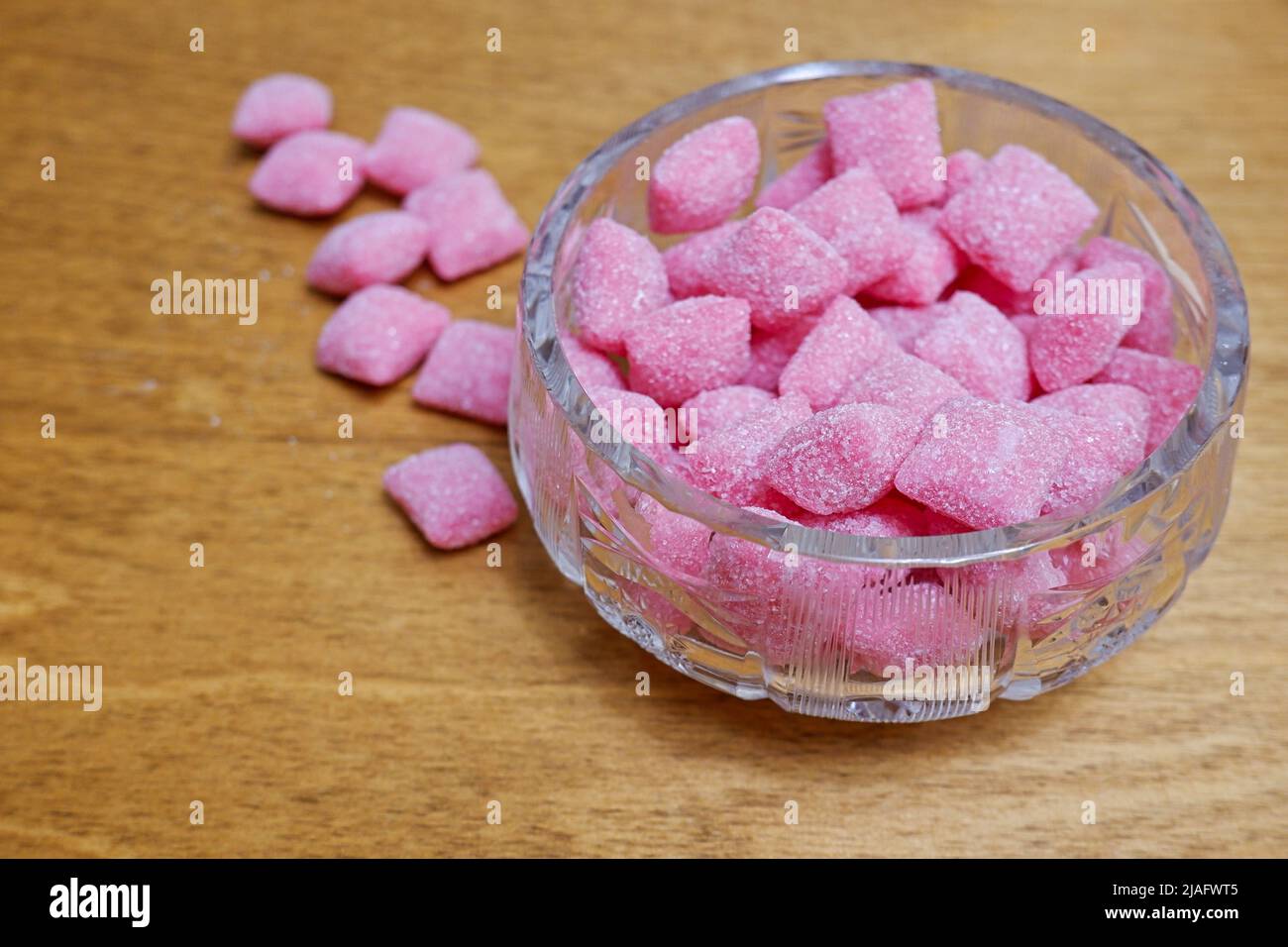 Kristallschale mit rosa Süßigkeiten auf dem Tisch Stockfoto