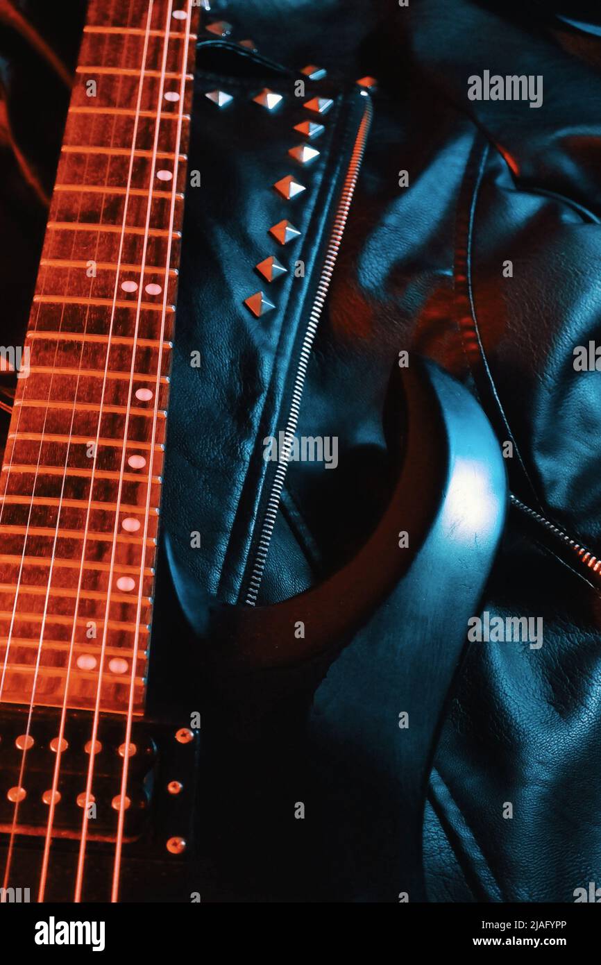 Schwarze E-Gitarre liegt auf einer Lederjacke Stockfoto
