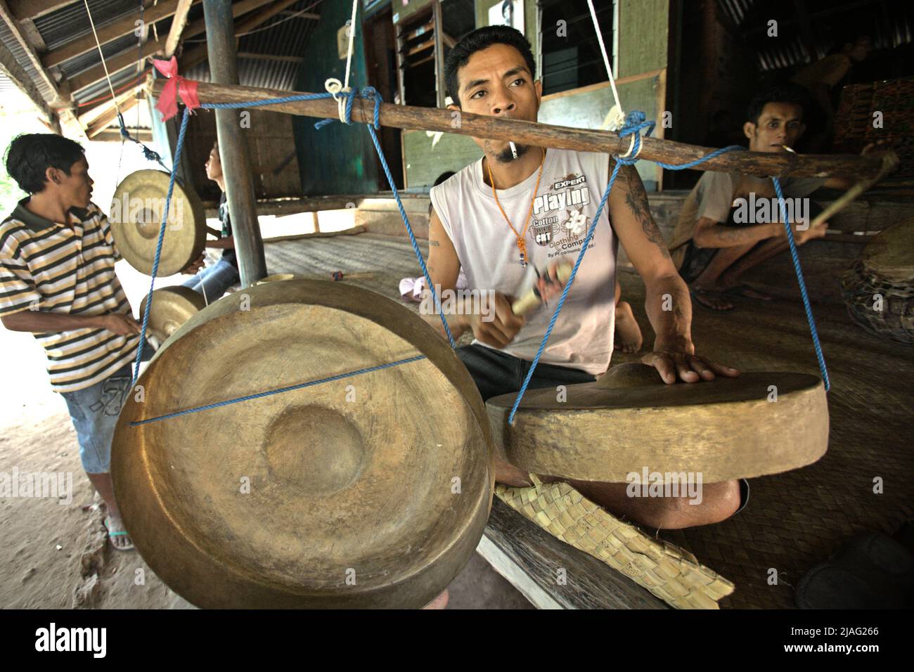 Männer, die während einer Trauersitzung Gongs spielten, als ein Mitglied ihrer Gemeinschaft, vergingen in Kilimbatu, Kawangu, Pandawai, East Sumba, East Nusa Tenggara, Indonesien. Gongs müssen nach dem lokalen Glaubenssystem (Marapu) gespielt werden, wenn jemand tot ist. Stockfoto